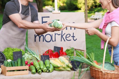 Photo of Woman choosing fresh vegetables from stall at farmer's market, closeup