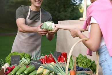 Photo of Woman choosing fresh vegetables from stall at farmer's market, closeup