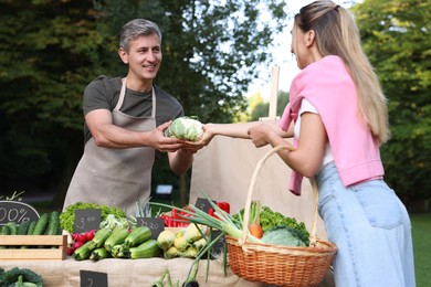 Photo of Woman choosing fresh vegetables from stall at farmer's market