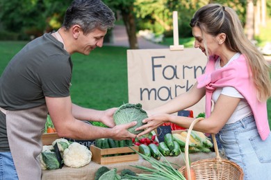 Photo of Woman choosing fresh vegetables from stall at farmer's market