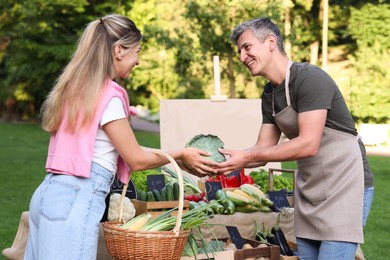 Photo of Woman choosing fresh vegetables from stall at farmer's market