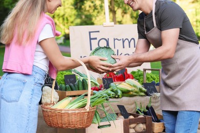 Photo of Woman choosing fresh vegetables from stall at farmer's market, closeup