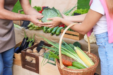 Photo of Woman choosing fresh vegetables from stall at farmer's market, closeup