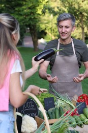 Photo of Woman choosing fresh vegetables from stall at farmer's market