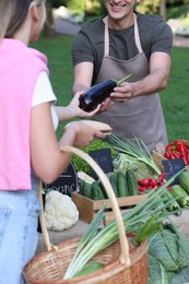Photo of Woman choosing fresh vegetables from stall at farmer's market, closeup