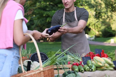 Photo of Woman choosing fresh vegetables from stall at farmer's market, closeup