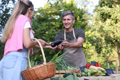 Photo of Woman choosing fresh vegetables from stall at farmer's market