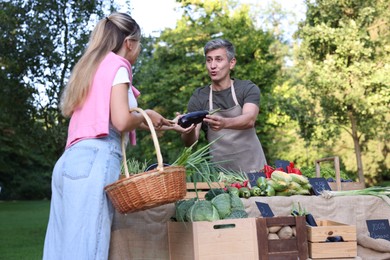 Photo of Woman choosing fresh vegetables from stall at farmer's market