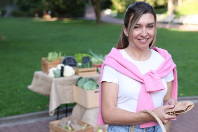 Photo of Woman holding wallet near stall at farmer's market
