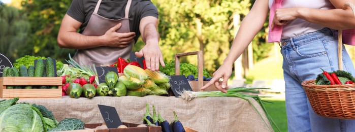 Photo of Woman choosing fresh vegetables from stall at farmer's market, closeup