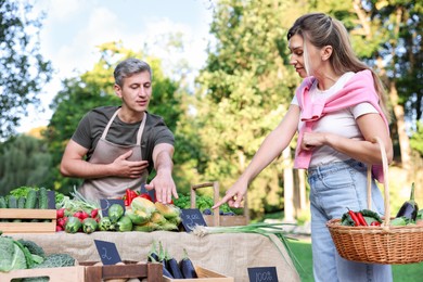 Photo of Woman choosing fresh vegetables from stall at farmer's market