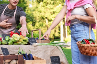 Photo of Woman choosing fresh vegetables from stall at farmer's market, closeup