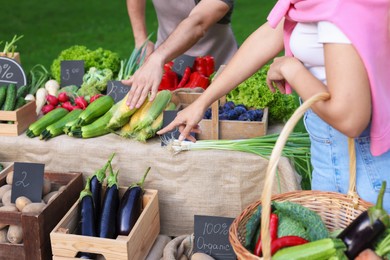 Photo of Woman choosing fresh vegetables from stall at farmer's market, closeup