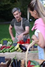 Photo of Woman choosing fresh vegetables from stall at farmer's market