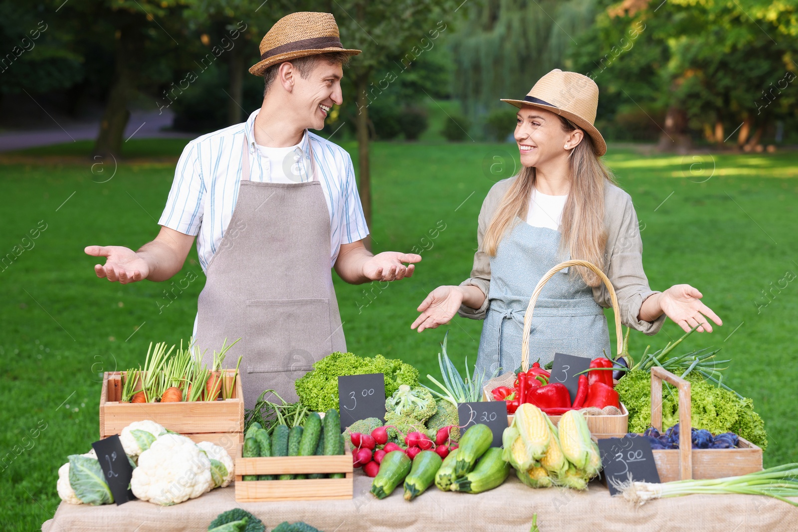 Photo of Happy farmers near stall with different fresh vegetables at market
