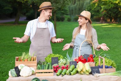Photo of Happy farmers near stall with different fresh vegetables at market