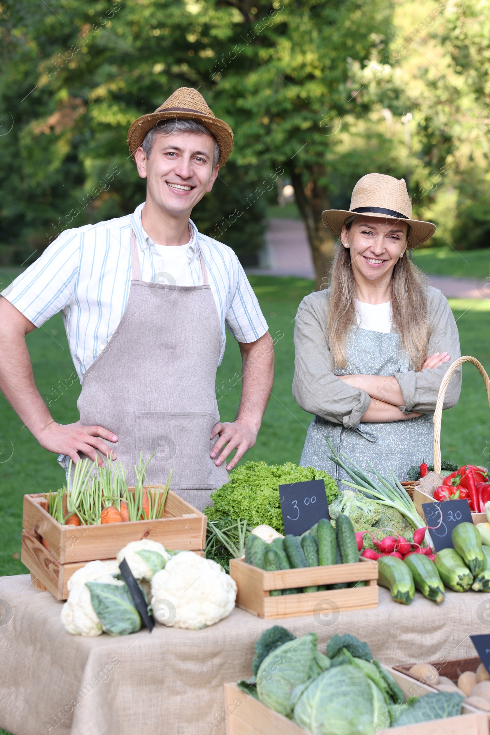 Photo of Happy farmers near stall with different fresh vegetables at market