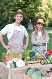 Photo of Happy farmers near stall with different fresh vegetables at market