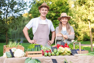Photo of Happy farmers near stall with different fresh vegetables at market