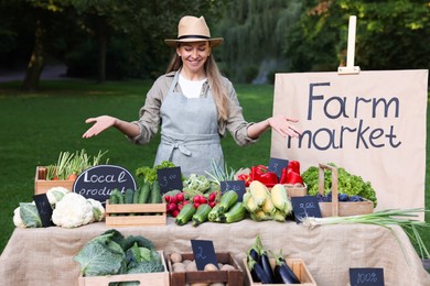 Photo of Farmer near stall with different fresh vegetables at market