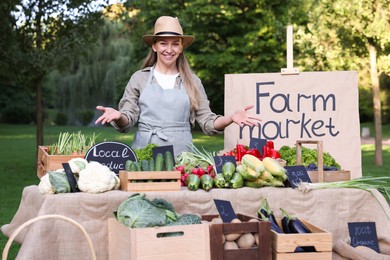 Photo of Farmer near stall with different fresh vegetables at market
