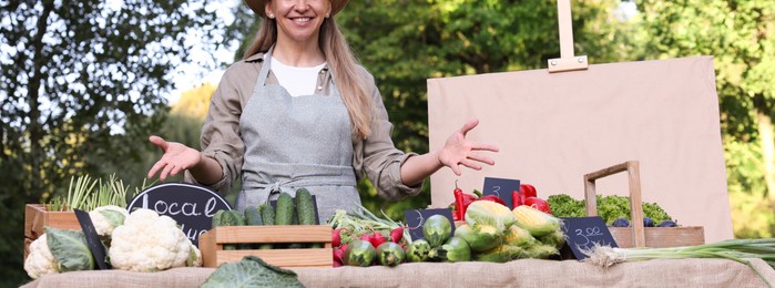 Photo of Farmer near stall with different fresh vegetables at market, closeup