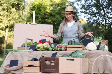 Photo of Farmer near stall with different fresh vegetables at market