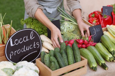 Photo of Farmer near stall with different fresh vegetables at market, closeup