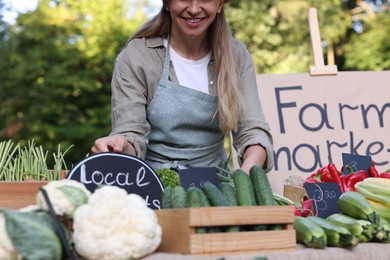 Photo of Farmer near stall with different fresh vegetables at market, closeup