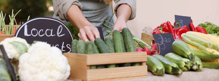 Photo of Farmer near stall with different fresh vegetables at market, closeup