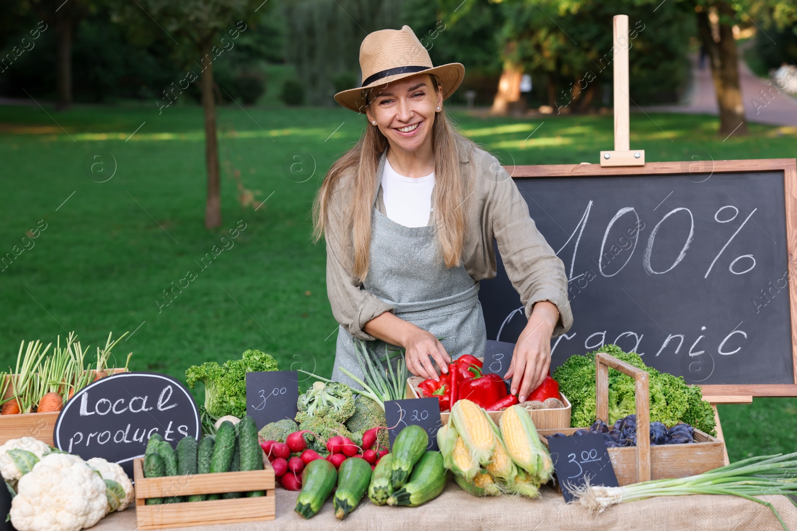 Photo of Happy farmer near stall with different fresh vegetables at market