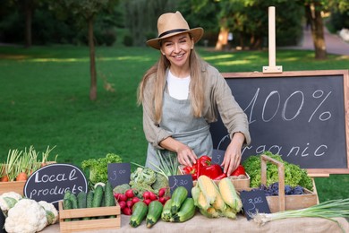 Photo of Happy farmer near stall with different fresh vegetables at market
