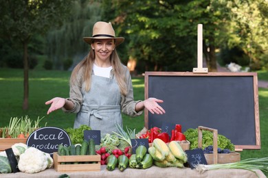 Photo of Happy farmer near stall with different fresh vegetables at market