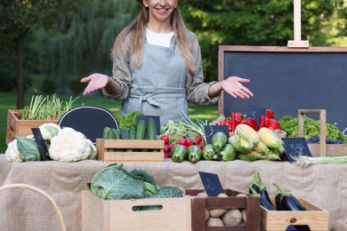 Photo of Farmer near stall with different fresh vegetables at market, closeup