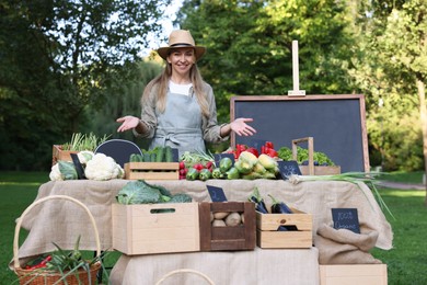 Photo of Happy farmer near stall with different fresh vegetables at market