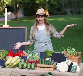 Photo of Happy farmer near stall with different fresh vegetables at market