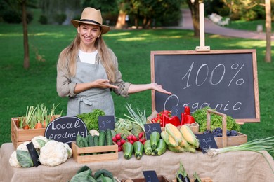 Photo of Happy farmer near stall with different fresh vegetables at market