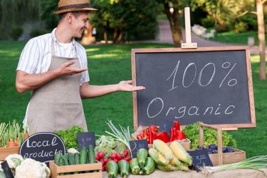 Photo of Happy farmer near stall with different fresh vegetables at market