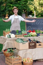 Photo of Happy farmer near stall with different fresh vegetables at market