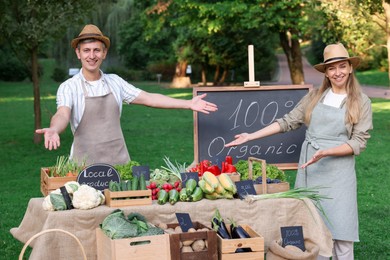 Photo of Happy farmers near stall with different fresh vegetables at market