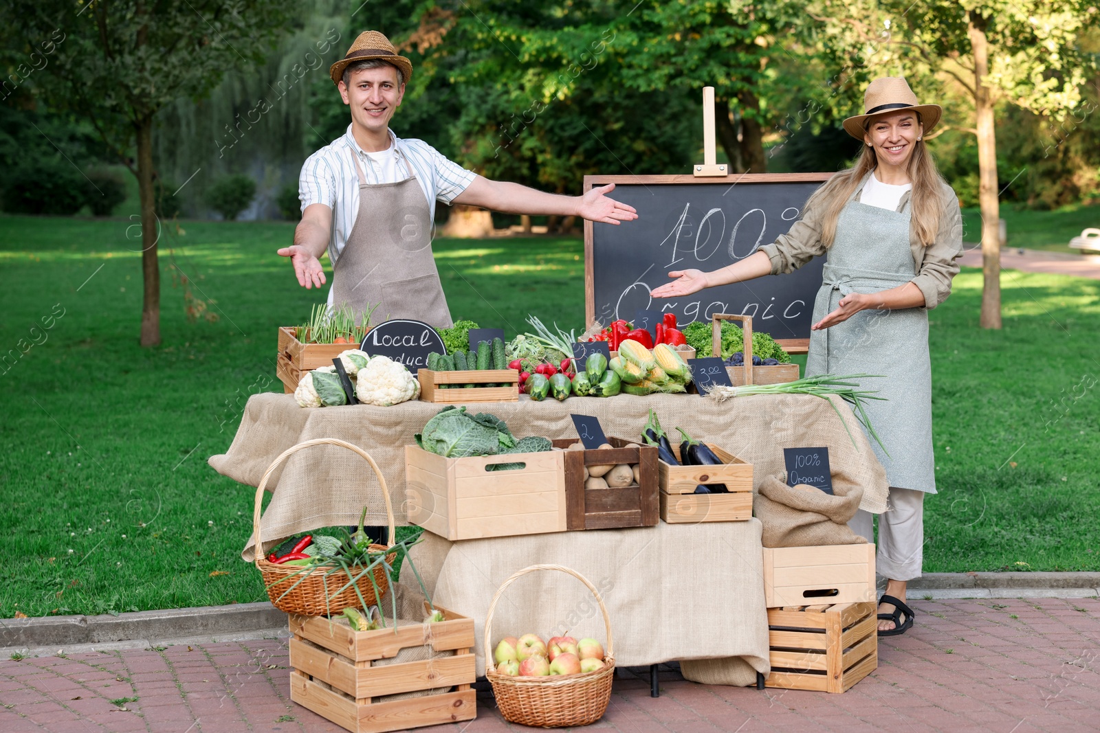 Photo of Happy farmers near stall with different fresh vegetables at market