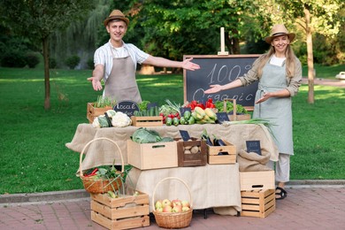 Photo of Happy farmers near stall with different fresh vegetables at market