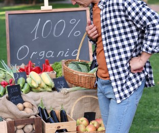 Photo of Man choosing fresh vegetables from stall at farmer's market, closeup