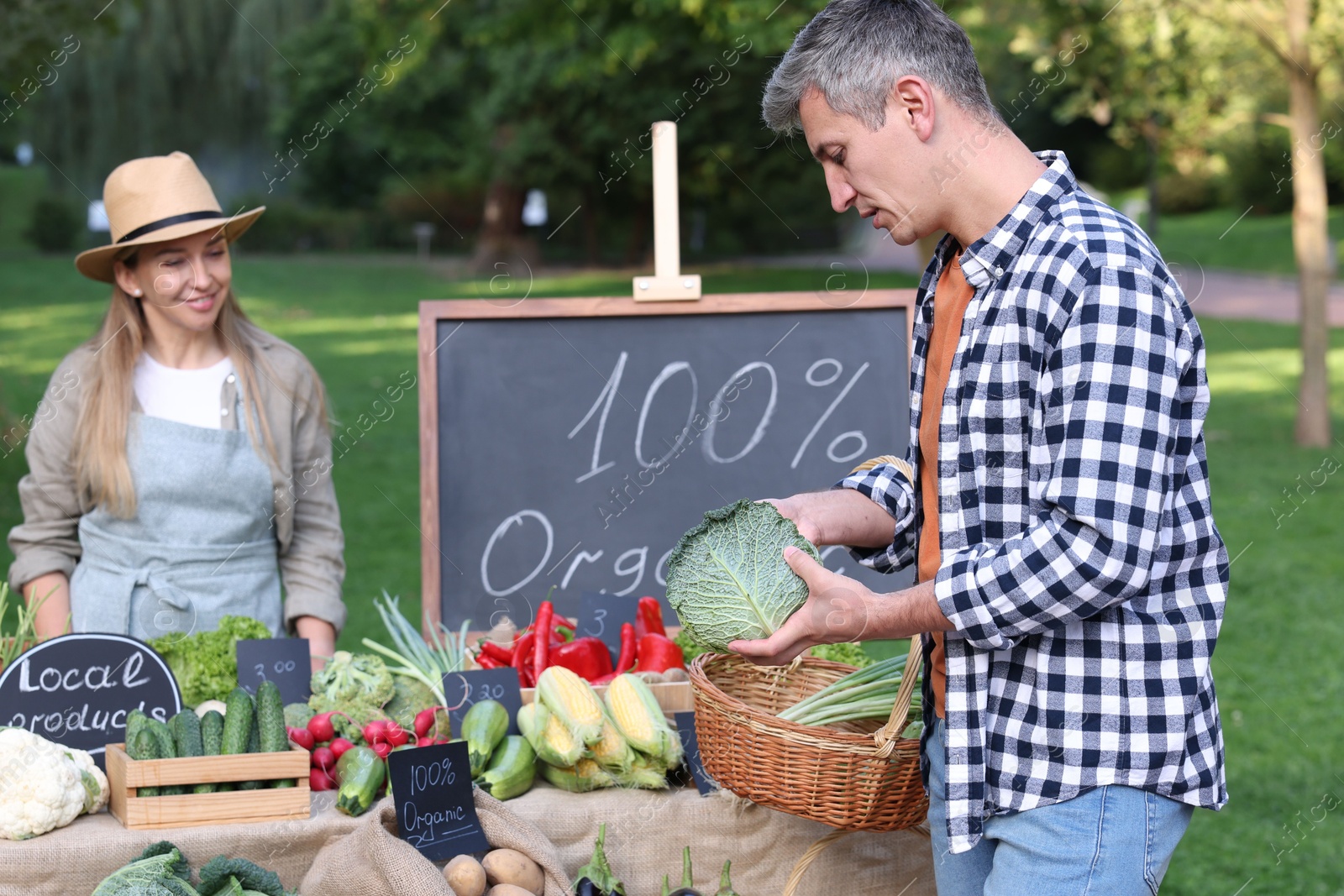 Photo of Man choosing fresh vegetables from stall at farmer's market