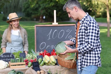 Photo of Man choosing fresh vegetables from stall at farmer's market