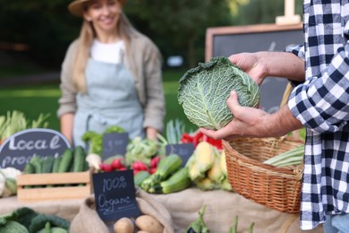 Photo of Man choosing fresh vegetables from stall at farmer's market, closeup