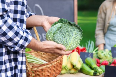 Photo of Man choosing fresh vegetables from stall at farmer's market, closeup