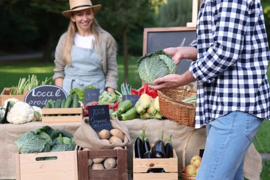Photo of Man choosing fresh vegetables from stall at farmer's market, closeup