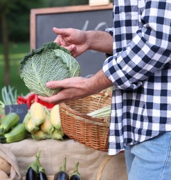 Photo of Man choosing fresh vegetables from stall at farmer's market, closeup