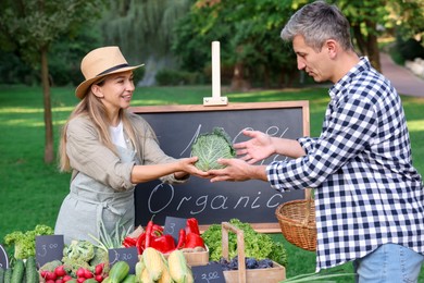 Photo of Man choosing fresh vegetables from stall at farmer's market